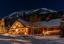 Winter cabin at night, lit up with warm colored lanterns.